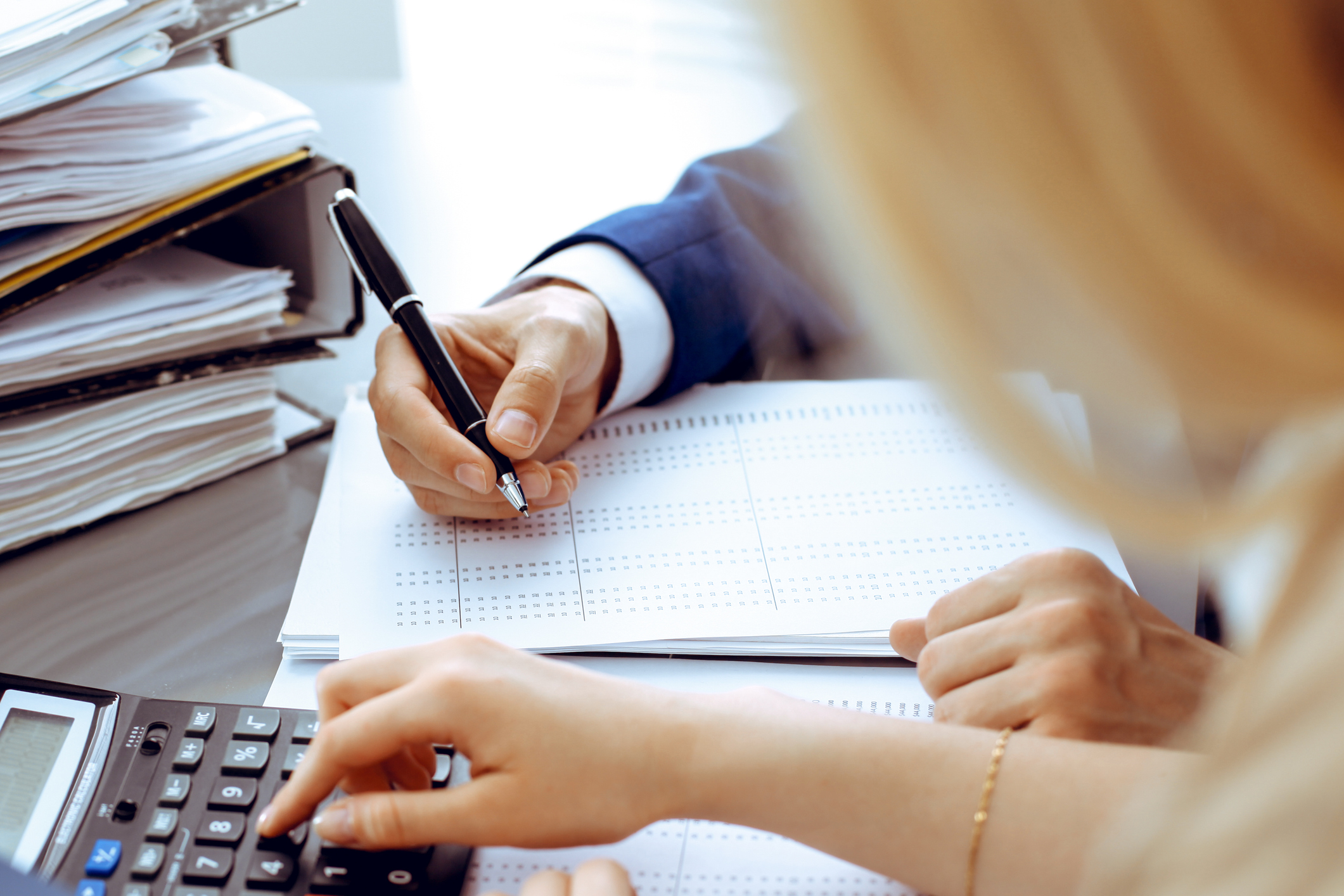 Bookkeeper or financial inspector and secretary making report, calculating or checking balance. Internal Revenue Service inspector checking financial document. Audit concept.