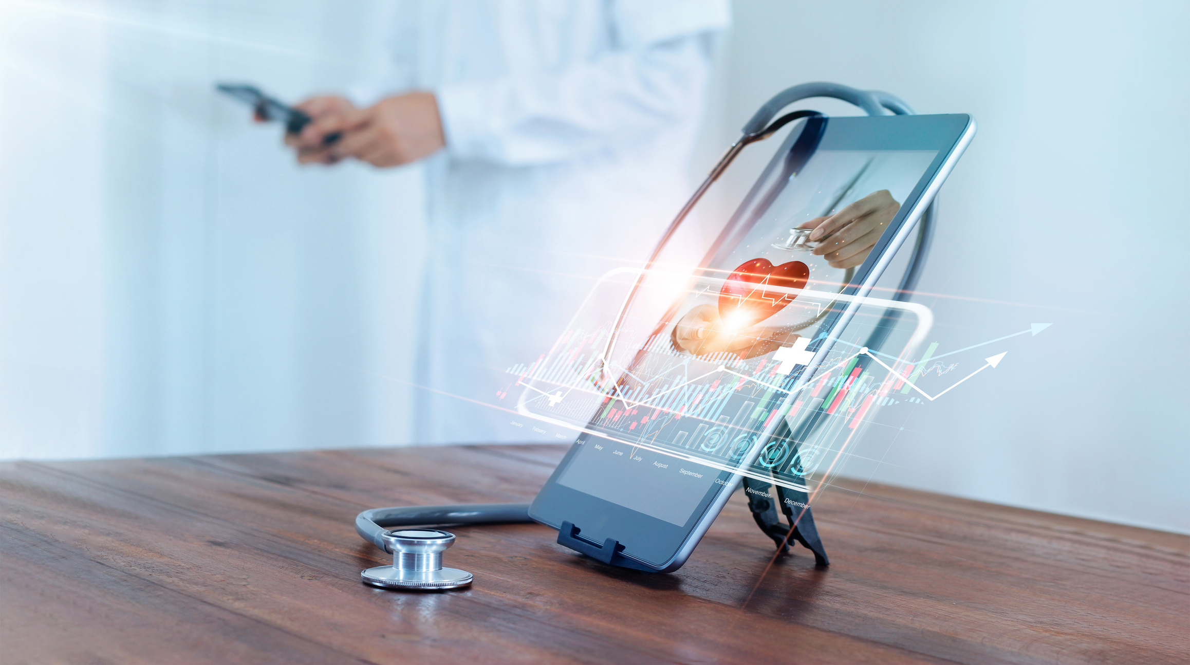 Medical examination and healthcare business via virtual interface technology.Doctor with stethoscope check and analysing patient heart health and increasing growth graph medical business on tablet.